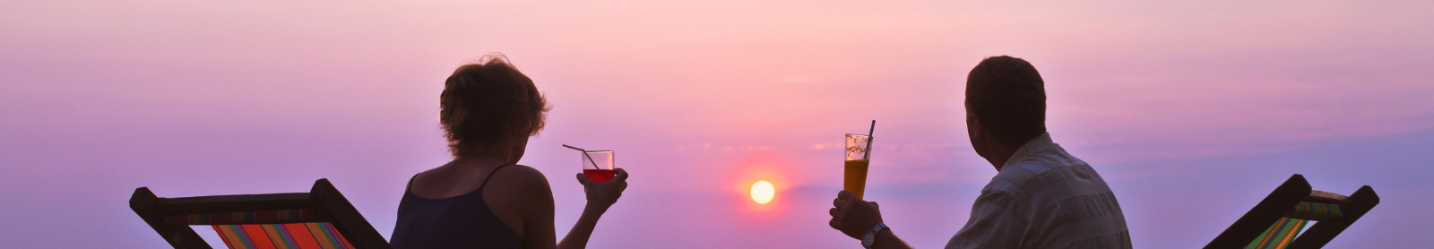 People relaxing on beach facing the sunset