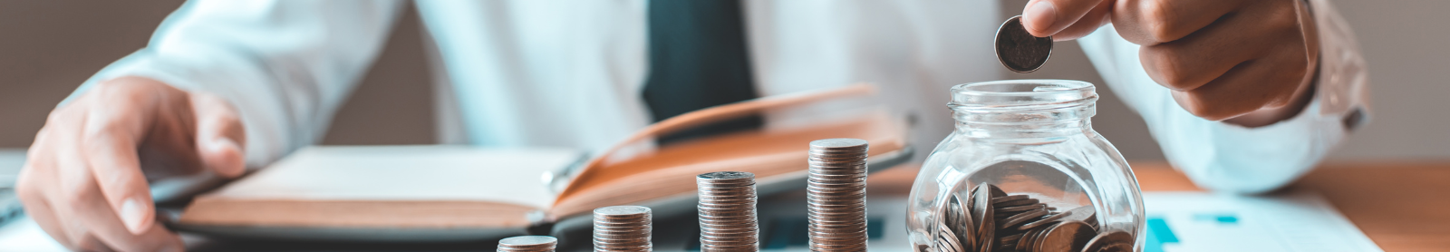 Photo of man putting coins into a savings jar