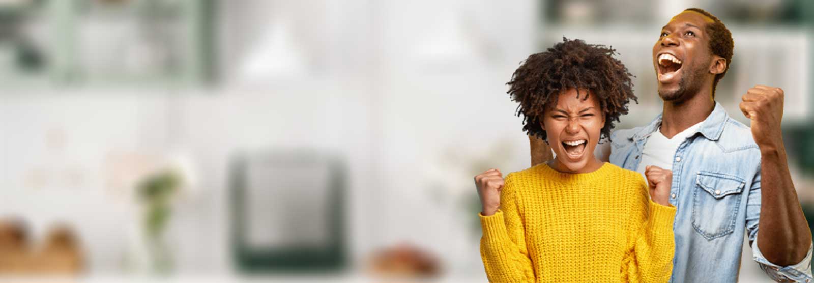 A vibrant, middle-aged couple celebrating with pumped fists and open smiles. The background of a home setting is blurred as the focus is on the couple.