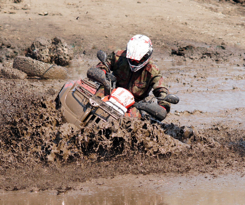 Man dirt biking through deep mud
