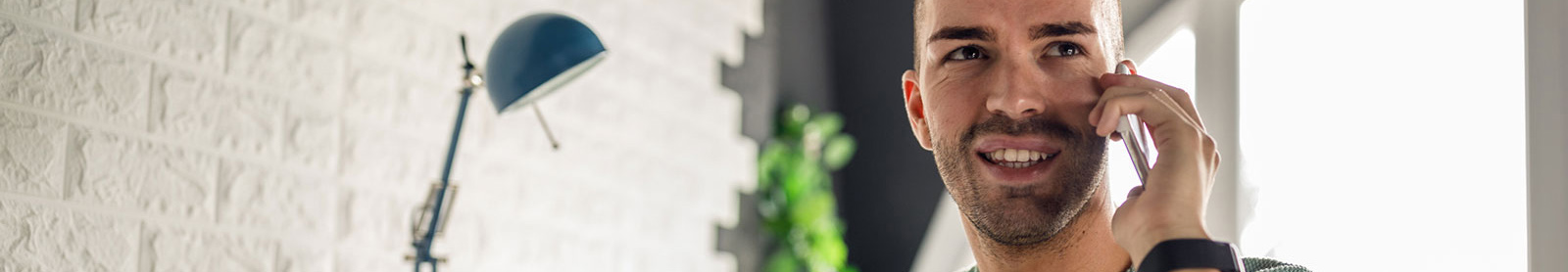 Young man talking on phone from home office