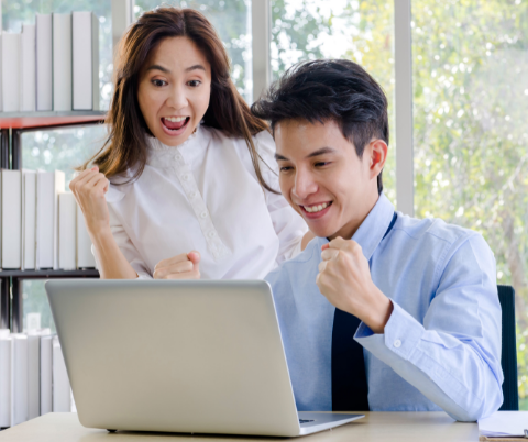 Photo of two people excited in front of a computer