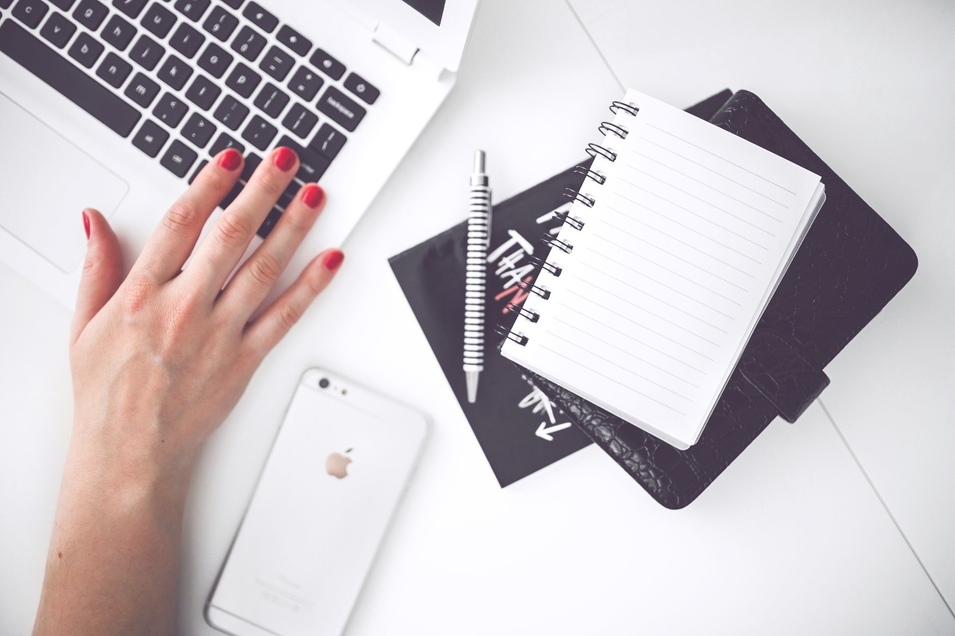 Person working on computer with notes and iphone on desk