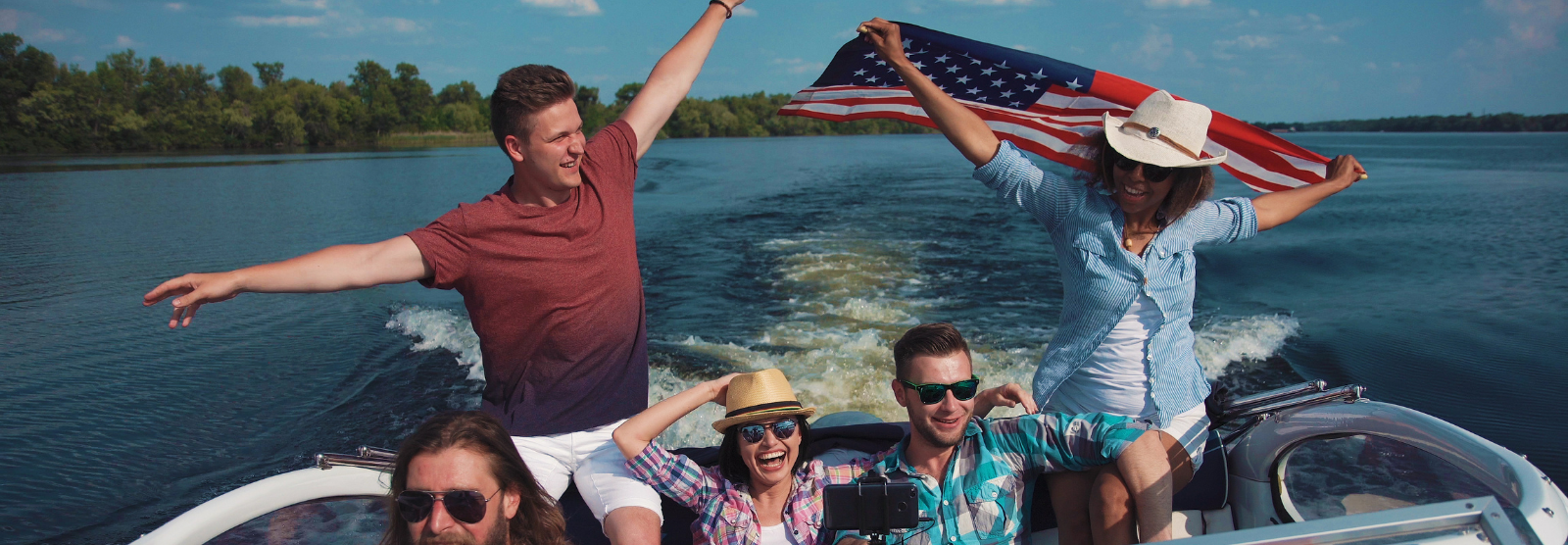 Photo of group of friends on a boat out on a lake. Hanging American flag in the background
